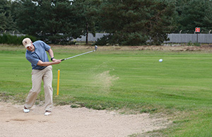 Golfer uding a wedge in the sand